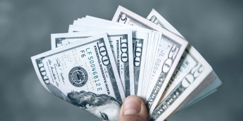 Person holding a handful of $100, $50, and $20 bills